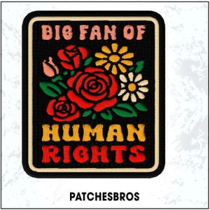 May include: Embroidered patch with a black background, featuring the text "BIG FAN OF HUMAN RIGHTS" in pink, yellow, and red. The patch includes a floral design with red roses, yellow daisies, and white flowers.