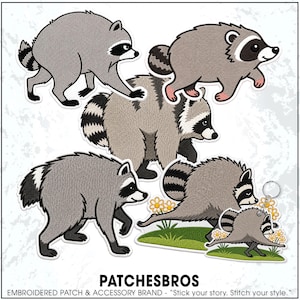 May include: A collection of embroidered patches and a keychain featuring cartoon raccoons in various poses. The designs include gray raccoons with black eye masks and striped tails, some standing on green grass with yellow flowers. Text reads PATCHESBROS.