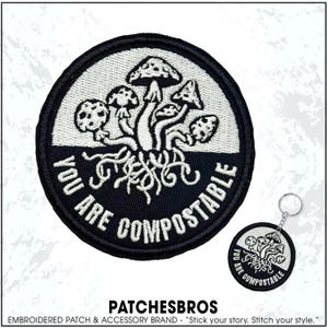 May include: Embroidered patch and keychain featuring a mushroom design with the text "YOU ARE COMPOSTABLE". The patch and keychain have a black border and a white and black mushroom graphic.