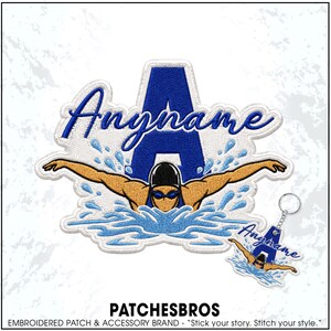 May include: An embroidered patch and matching keychain featuring a large blue letter A, a swimmer in a black cap and goggles performing a butterfly stroke, and blue water splashes. The text Anyname is embroidered in blue script across the patch.
