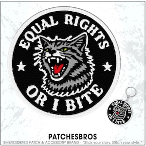 May include: Embroidered patch with a snarling cat design, the text "EQUAL RIGHTS OR I BITE" is in white. A matching keychain is also visible. The patch is black with white stitching and two white stars.