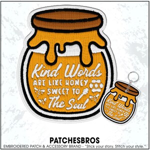 May include: Embroidered patch and keychain set featuring a honey jar design. The patch and keychain have a white border and text that reads "Kind Words Are Like Honey Sweet To The Soul." The honey jar is yellow and brown.