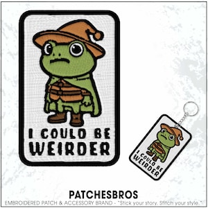May include: Embroidered patch and keychain featuring a green frog character wearing a brown hat and cape. The patch and keychain have the text "I COULD BE WEIRDER" in bold, black letters. The patch is rectangular with a black border.