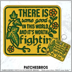 May include: A yellow embroidered patch and keychain with the text "THERE IS some good IN THIS WORLD, AND IT'S WORTH fighting for." Features green ivy and orange flowers. The keychain has a silver ring.