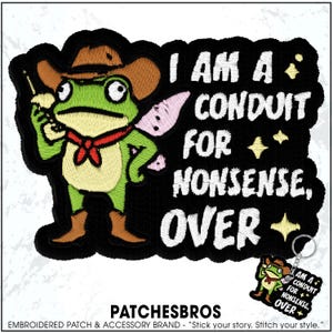 May include: Embroidered patch featuring a cartoon frog wearing a cowboy hat and holding a walkie-talkie. The patch reads "I AM A CONDUIT FOR NONSENSE, OVER" in white text on a black background. A small keychain with the same design is also visible.