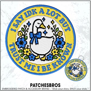 May include: A circular embroidered patch and matching keychain featuring a white goose with a blue bow, surrounded by blue and yellow flowers and stars. The text I SAY IDK A LOT BUT TRUST ME I BE KNOWN is stitched in blue along the yellow border.