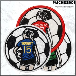 May include: Embroidered patches featuring soccer ball designs with female figures in team jerseys. One patch displays "VOUGHT 15" on a blue jersey, another shows "LEGION FC" on a red jersey. The patches are circular with black and white soccer ball backgrounds.