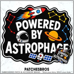 May include: A black embroidered patch featuring the white text POWERED BY ASTROPHAGE, a rocket, a planet with rings, a satellite, and constellations. A smaller matching keychain version is attached to the bottom right corner of the patch.