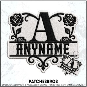 May include: An embroidered patch and a matching keychain featuring a large black letter A centered above a horizontal banner with the text ANYNAME, surrounded by black rose motifs on a white background with black decorative scrollwork borders.