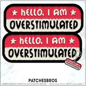 May include: Embroidered patches with the text "HELLO. I AM OVERSTIMULATED" in black and white on a red background. The patches have a black border and star accents. A keychain with the same design is also visible.