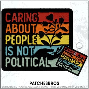 May include: Embroidered patch and keychain set with the text "CARING ABOUT PEOPLE IS NOT POLITICAL." The design features a hand holding a plant with a colorful sunset background. The patch is rectangular, and the keychain is square.