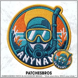 May include: A circular embroidered patch featuring a scuba diver in a teal wetsuit and mask with a snorkel. The background shows an orange sun and coral reefs. The text ANYNAME is stitched in white at the bottom. A smaller matching keychain is attached.
