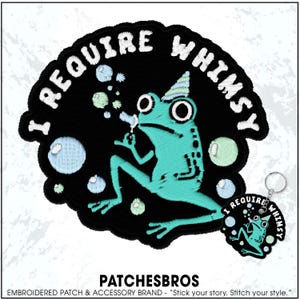May include: Embroidered patch featuring a teal frog wearing a party hat and blowing bubbles, with the text "I REQUIRE WHIMSY" in white. A matching keychain is also visible. The patch is black with a white border.