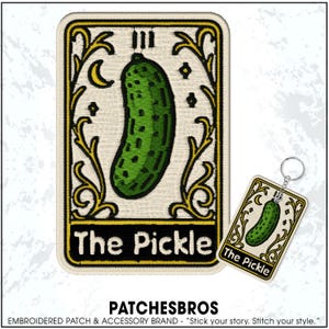 May include: Embroidered patch and keychain set featuring a green pickle tarot card design. The patch and keychain have a cream background with gold accents, a crescent moon, and the text "The Pickle."