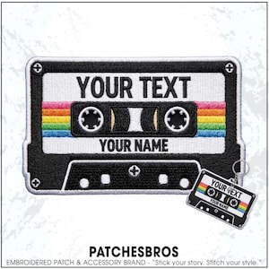 May include: An embroidered patch shaped like a cassette tape with black, white, and rainbow stripes, featuring the text YOUR TEXT and YOUR NAME. A matching keychain with the same cassette design and text is attached to the bottom right corner.