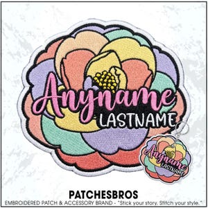 May include: An embroidered patch and a matching keychain featuring a stylized flower design with pastel petals in shades of pink, yellow, lavender, and mint green. The text "Anyname" and "LASTNAME" is embroidered in pink and white over the flower.