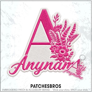 May include: An embroidered patch featuring a large white letter A with a bright pink border and a floral arrangement in pink thread on the right side. Below the letter, the word Anyname is embroidered in pink script. A smaller matching keychain is included.
