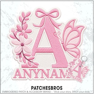 May include: An embroidered patch featuring a large pink letter A decorated with a pink bow, a butterfly, and floral sprigs, with the text ANYNAME below. A smaller matching keychain version is displayed in the bottom right corner.