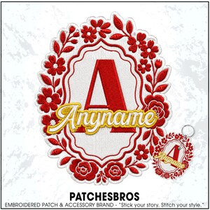May include: An embroidered patch and a matching keychain featuring a large red letter A centered within a white scalloped frame, surrounded by red floral embroidery. The word Anyname is stitched in yellow across the letter A. The text PATCHESBROS is below.