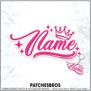 May include: A white embroidered patch featuring the word Name in bright pink cursive script, accented by a pink crown and four-pointed stars. A smaller matching keychain version of the design is attached to the patch by a silver metal ring.