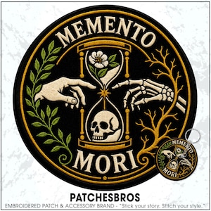 May include: A circular embroidered patch and a matching keychain featuring the text MEMENTO MORI. The design displays a central hourglass containing a white flower and a skull, flanked by a human hand and a skeleton hand, with green leaves and gold branches.
