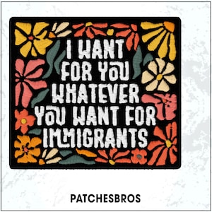 May include: Embroidered patch with the text "I WANT FOR YOU WHATEVER YOU WANT FOR IMMIGRANTS" in white on a black background. The patch is framed by colorful embroidered flowers in yellow, orange, pink, and white.