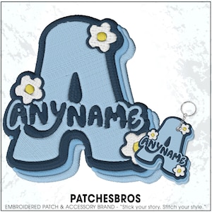 May include: Light blue embroidered patch and keychain featuring the letter "A" with the name "ANYNAME". The patch and keychain have a layered design with white and yellow flower accents. The brand name "PATCHESBROS" is at the bottom.