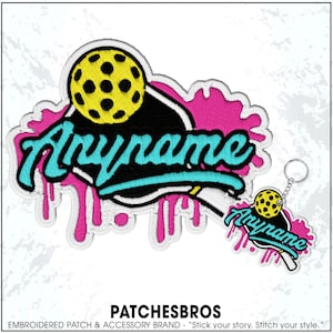 May include: Embroidered patch and keychain featuring a pickleball design with the word "Anyname" in teal script. The design includes a yellow pickleball and pink paint drip accents. The brand name "PATCHESBROS" is at the bottom.