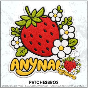 May include: An embroidered patch and a matching keychain featuring a bright red strawberry with black seeds, green leaves, and white flowers with yellow centers. The text ANYNAME is embroidered in bold yellow letters with a black outline.