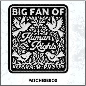 May include: Black and white embroidered patch with the text "BIG FAN OF Human Rights." The patch features stylized birds and floral designs. The brand name "PATCHESBROS" is printed at the bottom.