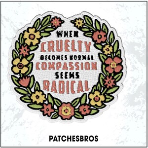 May include: Embroidered patch with a floral wreath design. The patch features the text "When Cruelty Becomes Normal Compassion Seems Radical" in a stylized font. The wreath includes yellow, red, and pink flowers with green leaves. The brand name "PATCHESBROS" is at the bottom.