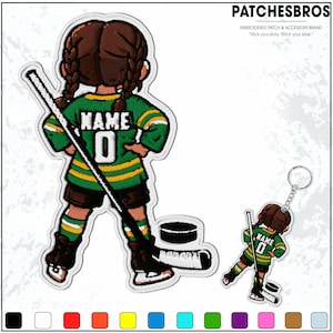 May include: Embroidered patch and keychain set featuring a cartoon hockey player in a green and yellow jersey with the name "NAME" and the number "0". The patch and keychain have a white border and include a hockey stick and puck.