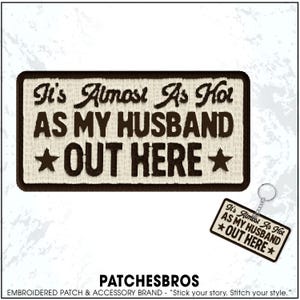 May include: A rectangular embroidered patch with a dark brown border and cream-colored background. The text reads It's Almost As Hot AS MY HUSBAND OUT HERE with a star on each side. A matching keychain version is shown in the bottom right corner.