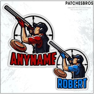 May include: Embroidered patches featuring a shooter aiming a shotgun at a clay target. One patch has the name "ANYNAME" in red, the other "ROBERT" in blue. The patches are set against a white background with the "PATCHESBROS" logo.