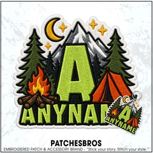 May include: An embroidered patch featuring a large lime green letter A and the text ANYNAME in lime green. The design includes a yellow crescent moon, yellow stars, grey mountains, dark green pine trees, a campfire, and an orange tent.