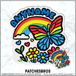 May include: An embroidered patch featuring a colorful butterfly, a rainbow, and flowers with the text ANYNAME arched above. A smaller matching keychain version is positioned in the lower right corner. The design uses vibrant red, yellow, blue, and green thread.