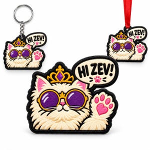 May include: A white cat embroidered patch, keychain, and ornament set. The cat wears a gold crown with a purple gem and purple-tinted sunglasses. A speech bubble reads HI ZEV! with a pink paw print. The cat has a raised paw with a pink heart.
