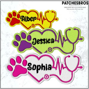 May include: Embroidered patches with names, paw prints, heart shapes, and stethoscopes. The patches feature the names "Alber", "Jessica", and "Sophia" in black script. The patches are in yellow, green, and pink with white and colored outlines.