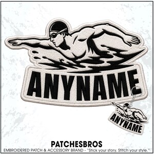 May include: An embroidered patch and a matching keychain featuring a black and white graphic of a swimmer in motion. The design includes the text ANYNAME in bold black capital letters on a white background with a stitched border finish.