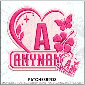 May include: A heart-shaped embroidered patch and matching keychain featuring a large pink letter A, a butterfly, a hibiscus flower, and the text ANYNAME. The design uses shades of pink and light pink thread on a light background.
