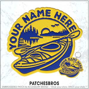 May include: A large circular embroidered patch and a matching smaller circular keychain featuring a yellow and blue design of a kayak on water with a forest and sun in the background. The text YOUR NAME HERE is embroidered in blue along the top.