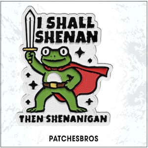May include: Embroidered patch featuring a green frog superhero holding a sword, wearing a red cape and a brown belt. Text reads "I SHALL SHENAN" above the frog and "THEN SHENANIGAN" below. The brand name "PATCHESBROS" is at the bottom.