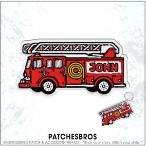 May include: An embroidered patch and a matching keychain featuring a red fire truck with a white ladder on top, a yellow coiled hose on the side, and the name JOHN in black letters on a white background. The design includes black outlines.