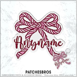 May include: An embroidered patch featuring a pink and dark red rope-style bow with the text Anyname in a cursive font. A smaller matching keychain version of the bow with the same text is positioned in the lower right corner of the image.