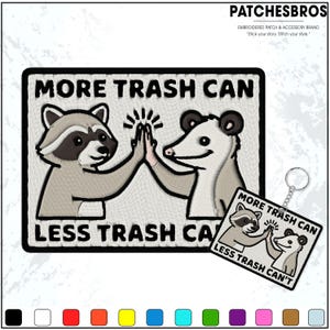 May include: Embroidered patch with a raccoon and opossum high-fiving, with the text "MORE TRASH CAN" and "LESS TRASH CAN". A matching keychain is also visible. The patch is rectangular with a black border.