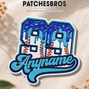 May include: An embroidered patch featuring the number 99 with a blue icing drip design and colorful sprinkles. The number is patterned with red baseball stitching. Below, the word Anyname is embroidered in a blue script font with a white outline.