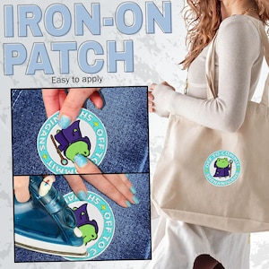 K&ouml;nnte beinhalten: Ein B&uuml;gelbild mit dem Text "IRON-ON PATCH" und "Easy to apply". Der Aufn&auml;her zeigt einen Cartoon-Frosch in einem Zauberer-Outfit mit den Worten "OFF TO COMMIT SHENANIGANS". Der Aufn&auml;her wird auf Denim aufgeb&uuml;gelt.