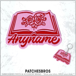 May include: Pink embroidered patch and keychain featuring an open book design with red roses and the word "Anyname". The patch and keychain are from the brand PATCHESBROS.