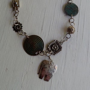 Upcycled necklace made of vintage jewelry components and found objects, with a silver elephant pendant