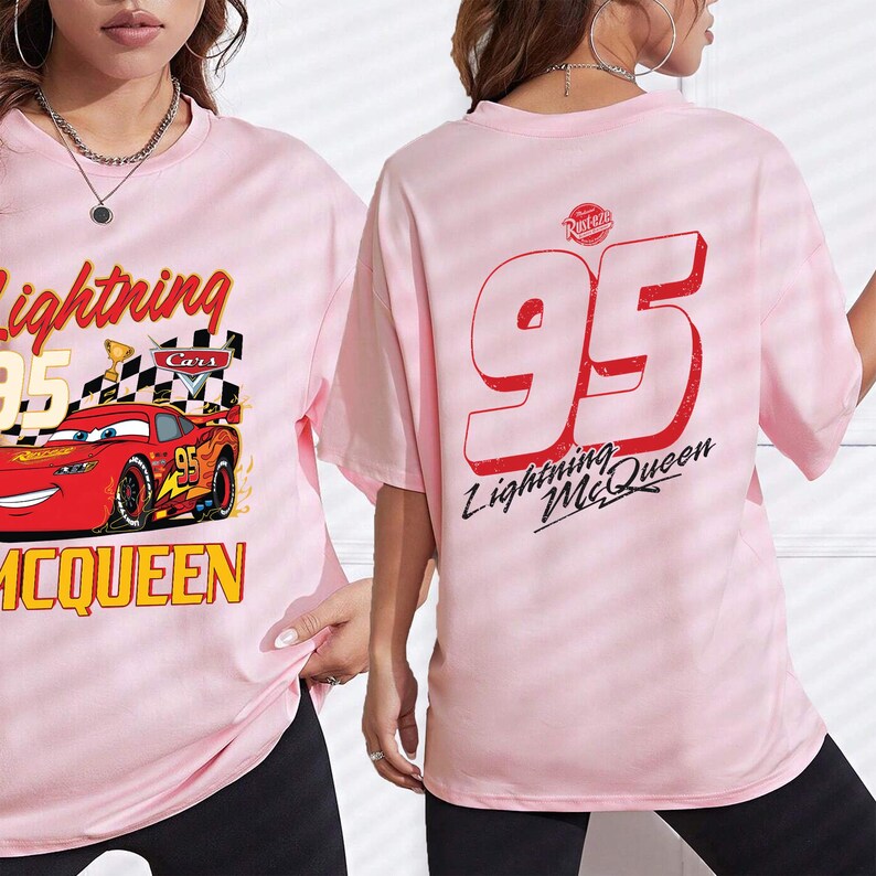 Puede incluir: Camiseta rosa claro con Lightning McQueen de la pel&iacute;cula Cars. El frente muestra el coche, el n&uacute;mero 95 y la frase "Lightning McQueen". La parte trasera tiene un gran "95" rojo y "Lightning McQueen".